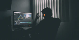 shallow focus photography of man listing to music in front of the computer