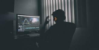 shallow focus photography of man listing to music in front of the computer