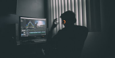 shallow focus photography of man listing to music in front of the computer game teams background
