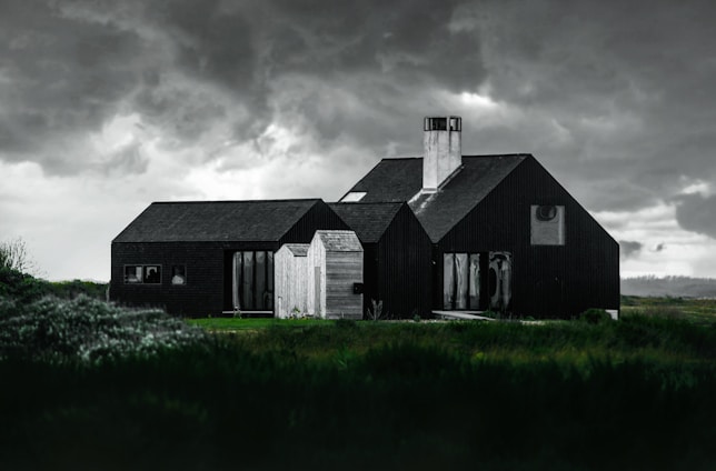A sturdy, modern home surrounded by lush greenery under a cloudy sky, symbolizing strength against storms.