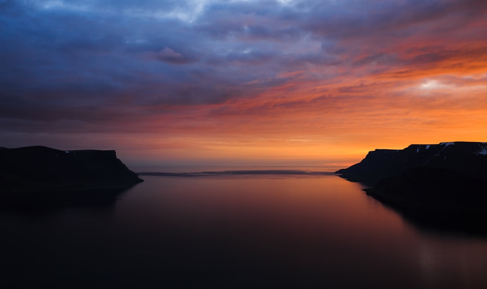 body of water under orange sunset