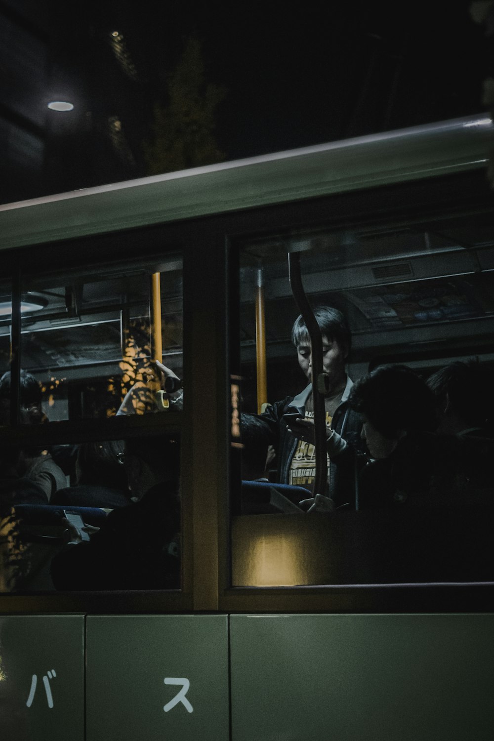 Persona in piedi all'interno del treno mentre utilizza lo smartphone davanti alla finestra di vetro trasparente