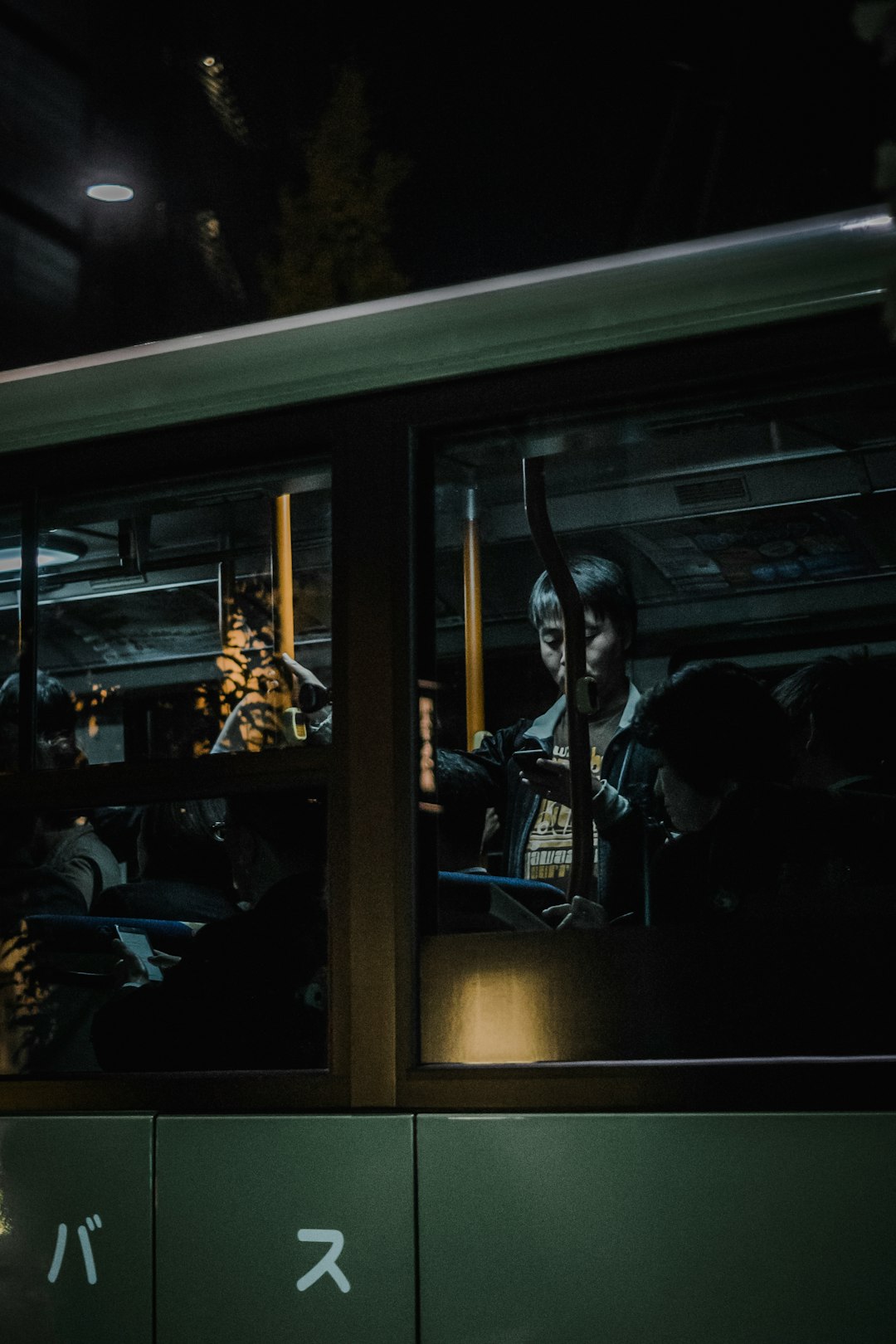 person standing inside train while using smartphone in front of clear glass window