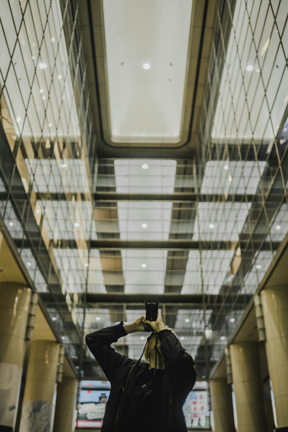 man holding DSLR camera while taking photo in hallway