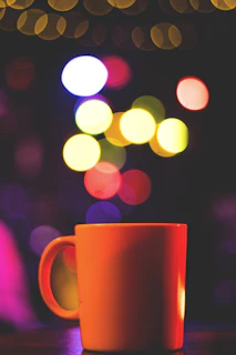 Close-up of a glossy printed mug featuring a personalized photo and text, resting on a bright orange background.