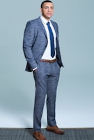 A sharp formal suit paired with a crisp white shirt and royal blue tie set in an urban evening setting.