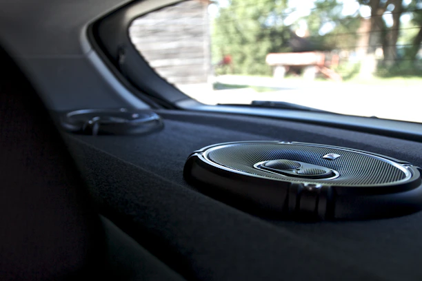 Close-up of a sleek car door panel showcasing a custom-installed premium speaker with ambient lighting.