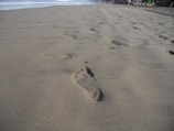 Wide view of a peaceful beach with footprints leading towards the horizon