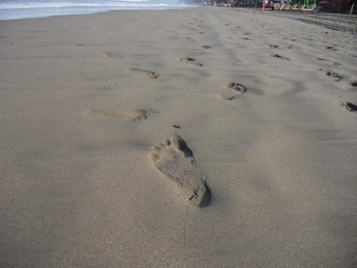 A peaceful beach scene with footprints in the sand leading towards the rolling Atlantic waves.