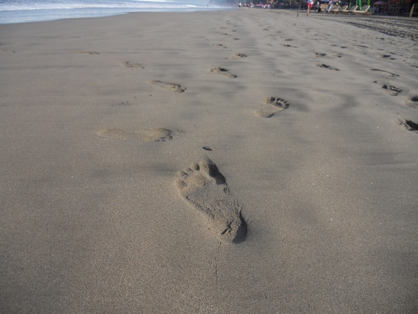 A tranquil beach scene with footprints leading towards the horizon.