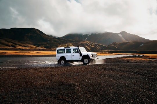 white car crossing body of water in Landmannalaugar Iceland
