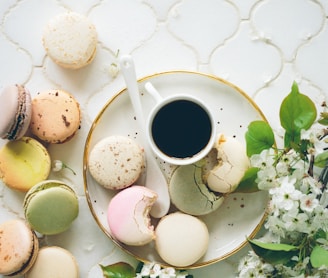 macarons beside teacup and ladle on round white ceramic plate