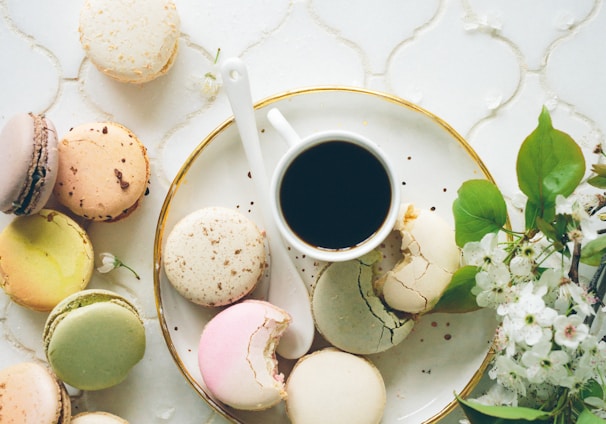 macarons beside teacup and ladle on round white ceramic plate
