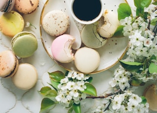 macarons beside teacup and ladle on round white ceramic plate