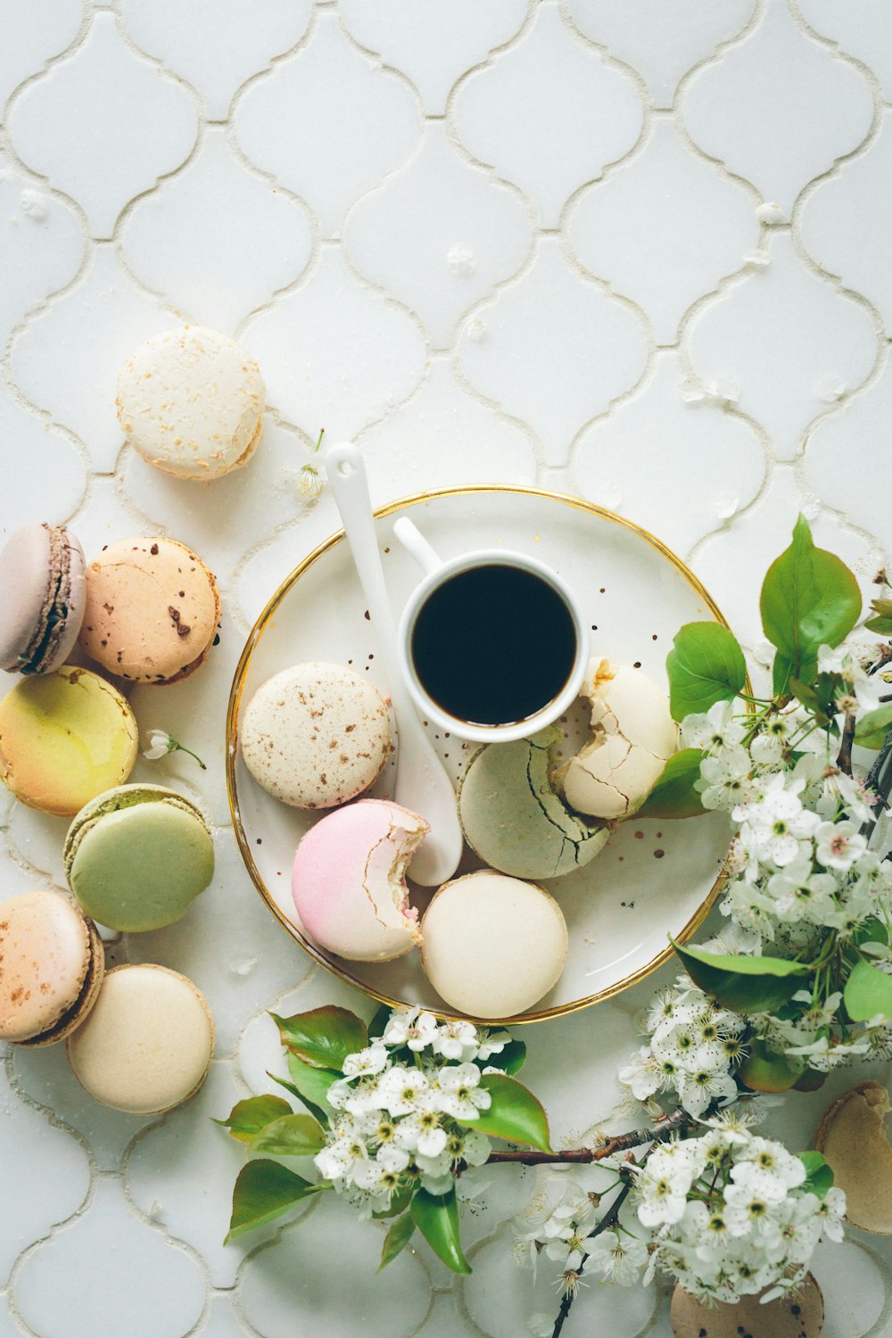 macarons ao lado de xícara de chá e concha em placa redonda de cerâmica branca