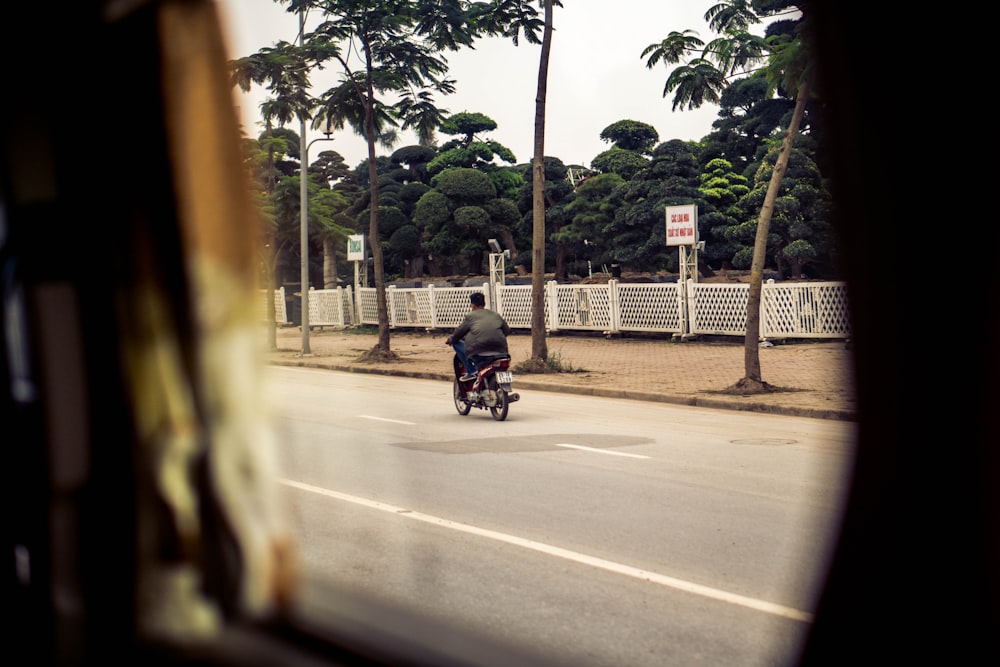 man riding motorcycle beside trees