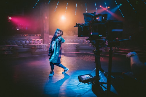 woman dancing on stage near black cameras