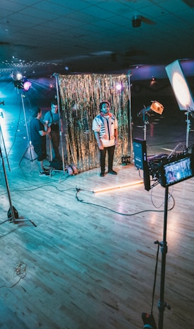 man standing in front of cameras with string lights background