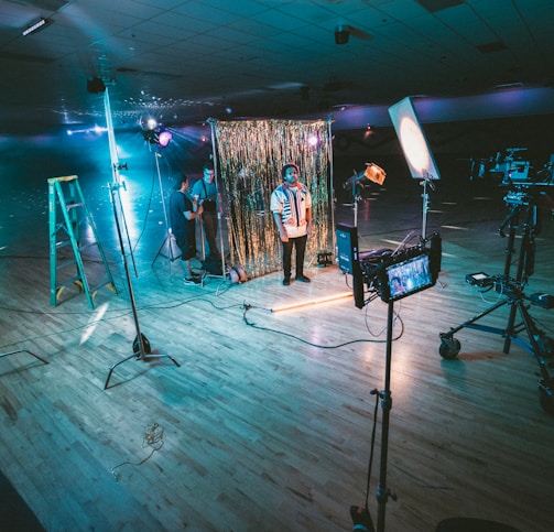 man standing in front of cameras with string lights background