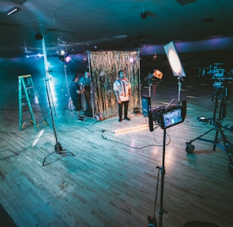 man standing in front of cameras with string lights background