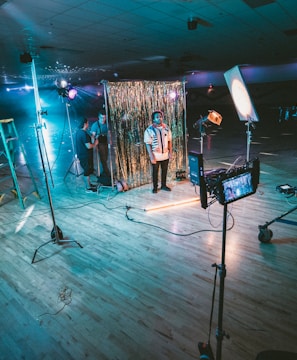 man standing in front of cameras with string lights background