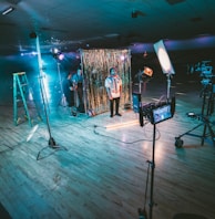 man standing in front of cameras with string lights background