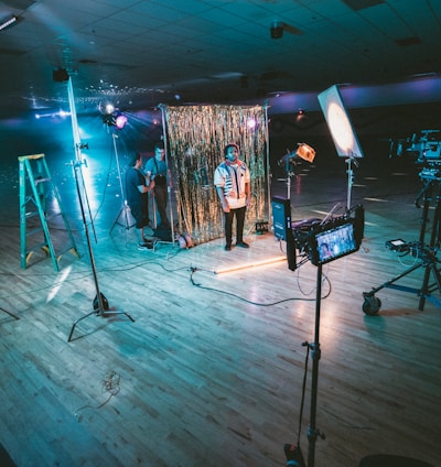 man standing in front of cameras with string lights background