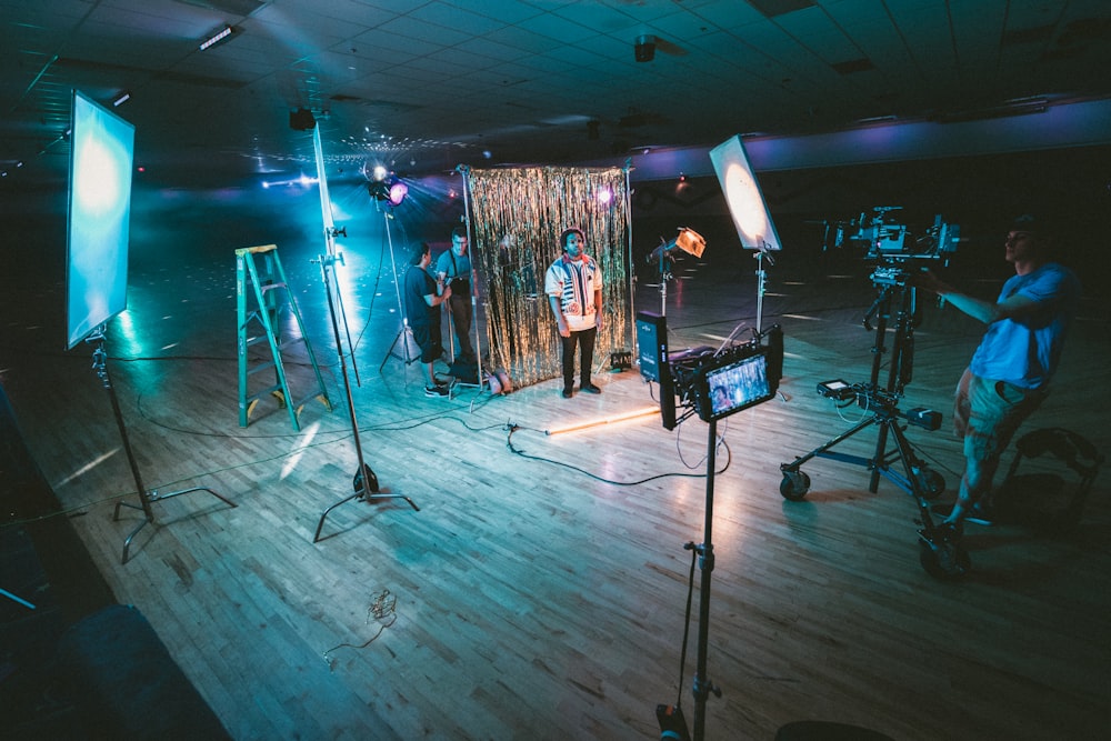 man standing in front of cameras with string lights background