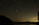 A vibrant night sky filled with stars and a glowing moon over a calm landscape.