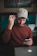 Happy young man using a smartphone while reading tech reviews on a laptop.