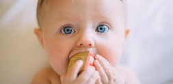 selective focus photography of baby holding wooden cube