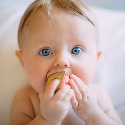 selective focus photography of baby holding wooden cube