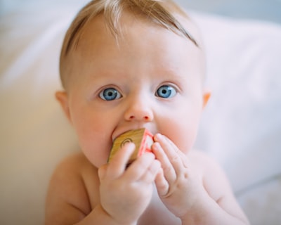 selective focus photography of baby holding wooden cube baby google meet background