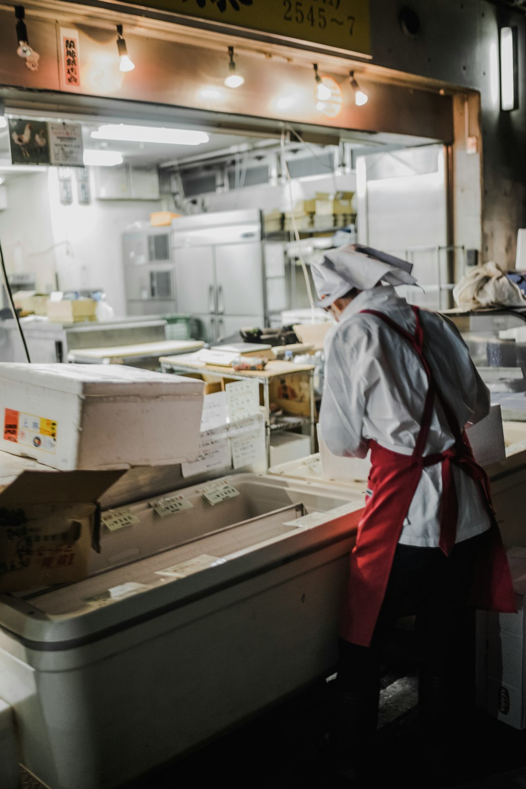 person with red apron standing beside machine