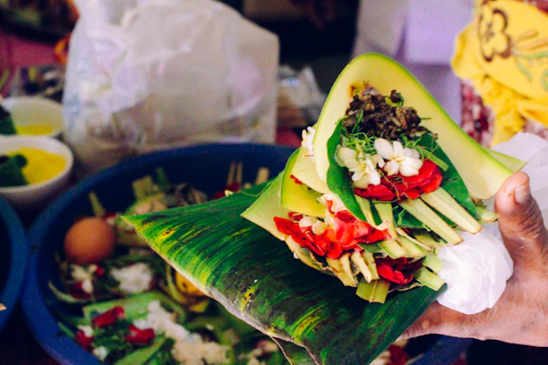 Close-up of hands holding traditional ritual objects with natural elements in the background.