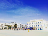 A bustling plaza in San Vicente del Caguán with shoppers enjoying local stores under a bright sky.