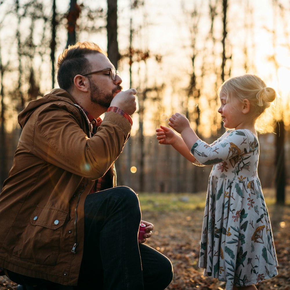 A man playing with his kindergarten aged daughter outside.