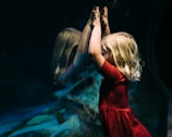 girl leaning on glass fish tank raising her two hands