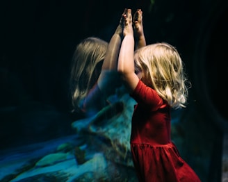 girl leaning on glass fish tank raising her two hands