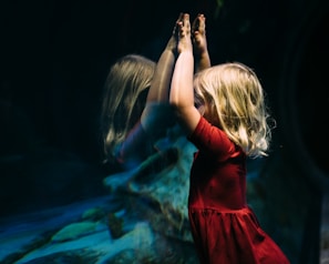 girl leaning on glass fish tank raising her two hands