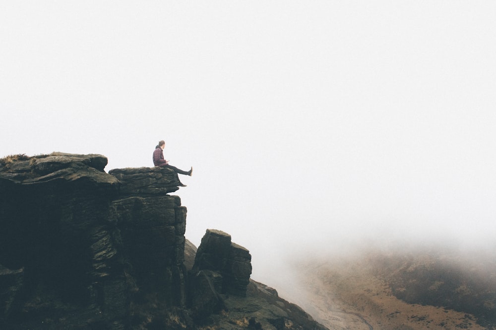 person sitting on gray rock formation