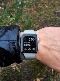 Runner checking smartwatch data during morning jog in a park.