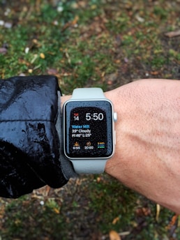 Runner checking smartwatch data during morning jog in a park.