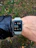 A man jogging in a park wearing a sleek smartwatch with a clear display.