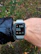 A man jogging in a park wearing a sleek smartwatch with a clear display.