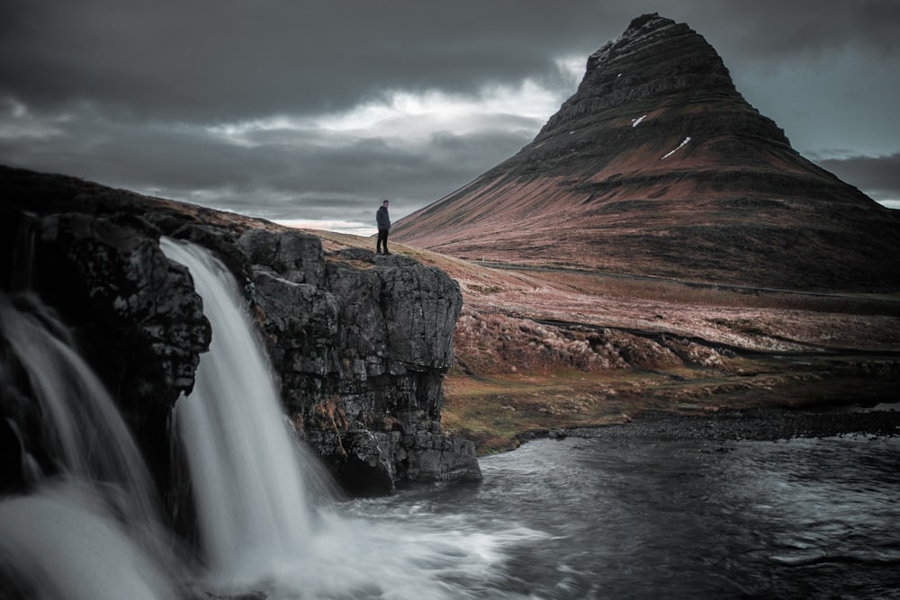 photography of man standing of top of mountain