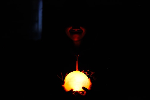 A glowing orb floating above a person's palm in a dark room.
