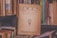 A vintage journal titled 'Logos Revista de la Facultad de Filosofía y Letras' is prominently placed among a collection of various books on a cluttered shelf. The worn, yellowed cover contains textual elements and an illustration of a bearded figure. The surrounding books have colorful but faded covers, contributing to a nostalgic and scholarly atmosphere.