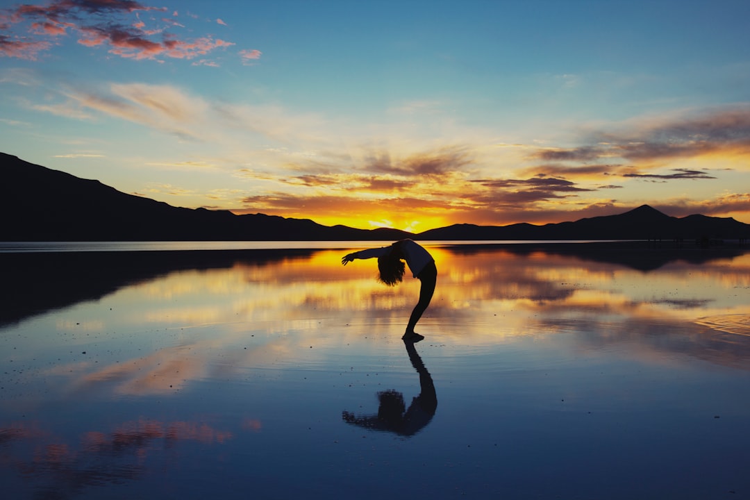 A person doing yoga on the Uyuni Salt Flat during sunset