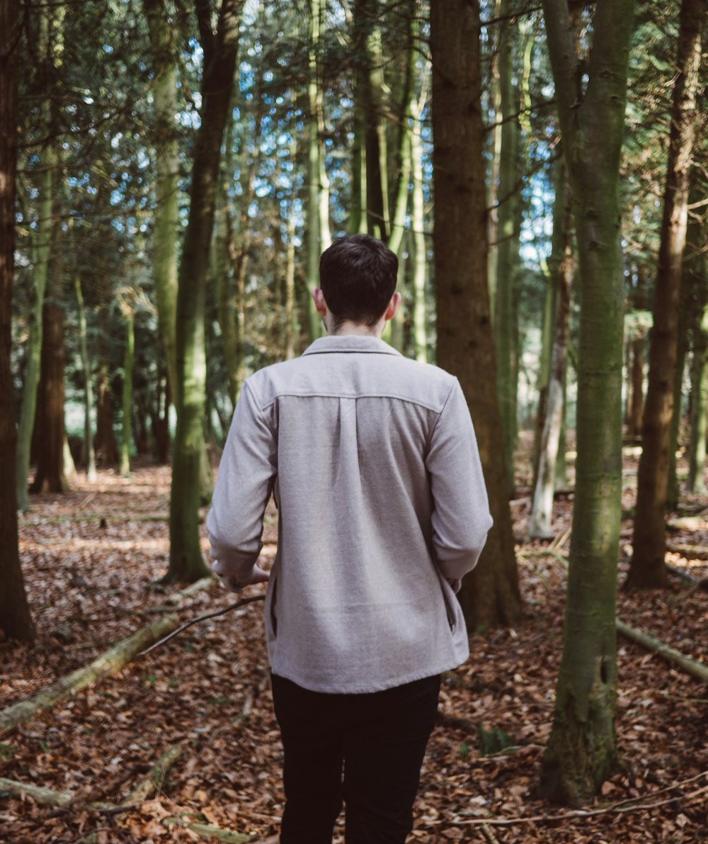 man walking in forest surrounded by trees during daytime